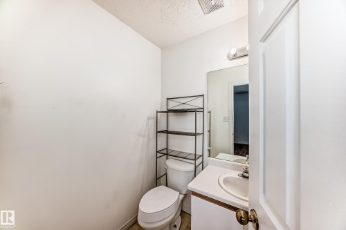 Bathroom featuring a vanity with a sink, a mirror, and a toilet - 1832 42 Street, Edmonton, AB - Indoor Photo Showing Bathroom