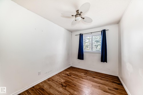 This room features wood flooring, a window with blue curtains, and a ceiling fan - 1832 42 Street, Edmonton, AB - Indoor Photo Showing Other Room