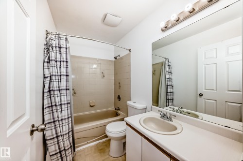The bathroom features a vanity with an integrated sink, a large mirror, and a bathtub with a shower - 1832 42 Street, Edmonton, AB - Indoor Photo Showing Bathroom