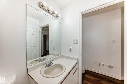 Bathroom featuring a vanity with an integrated sink, a large wall-mounted mirror, and a light fixture with four bulbs - 1832 42 Street, Edmonton, AB - Indoor Photo Showing Bathroom