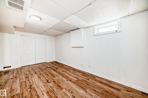The property features durable wood-look flooring, white walls, and a drop ceiling with recessed lighting - 1832 42 Street, Edmonton, AB - Indoor Photo Showing Other Room