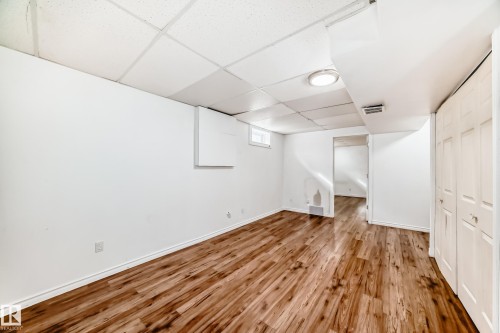 This bright room features wood-style flooring, white walls, and a drop ceiling with recessed lighting - 1832 42 Street, Edmonton, AB - Indoor Photo Showing Other Room