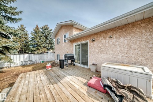 The property features an extensive deck with wooden planks, a sliding glass door leading into the home, and a textured exterior finish - 1832 42 Street, Edmonton, AB - Outdoor With Deck Patio Veranda With Exterior
