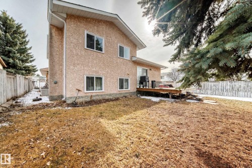 The property features an extensive yard with a wooden fence and mature trees - 1832 42 Street, Edmonton, AB - Outdoor With Exterior