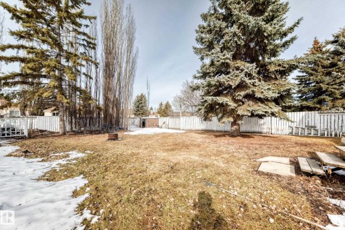 The property features a spacious yard with a white picket fence, mature trees, and a ground-level patio area - 1832 42 Street, Edmonton, AB - Outdoor