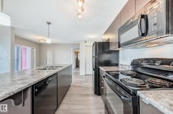 The kitchen features black appliances, including a microwave, oven, and refrigerator - 