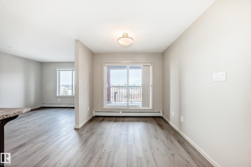 This bright interior features plank flooring, light neutral walls, and a ceiling light fixture - 332 344 Windermere Road, Edmonton, AB - Indoor Photo Showing Other Room