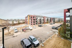 The property features a multi-story building with balconies, surrounded by a paved parking area and landscaped grounds - 