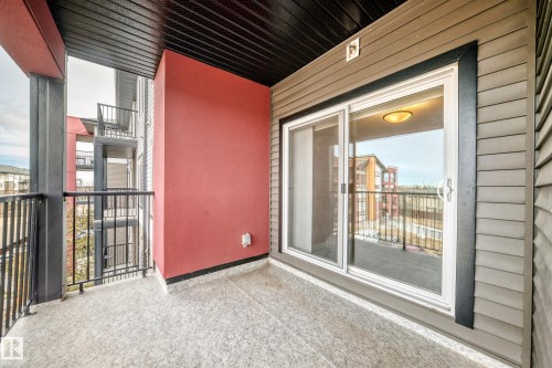The property features a private balcony with a concrete floor, black metal railings, and a red accent wall - 332 344 Windermere Road, Edmonton, AB - Outdoor With Balcony With Exterior