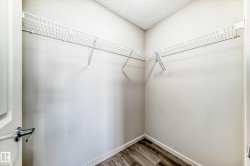 Closet featuring white wire shelving, light-colored walls, and wood-look flooring - 