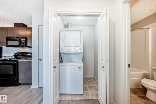 The property includes a stacked washer and dryer unit, providing convenient laundry access - 332 344 Windermere Road, Edmonton, AB - Indoor Photo Showing Laundry Room