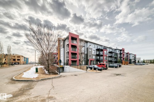 The property features a multi-story building with a modern exterior design, incorporating red and grey cladding - 332 344 Windermere Road, Edmonton, AB - Outdoor With Balcony With Facade