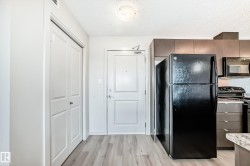 The property features wood-style flooring, a white paneled door, and a black refrigerator - 