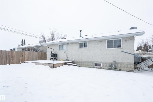 The property features a backyard with a wooden fence and a raised wooden deck - 4420 56 Avenue, Barrhead, AB - Outdoor