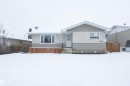 This property features a single-story home with light-colored stucco and horizontal siding, a light-colored entry door, and a front yard with a wooden fence - 4420 56 Avenue, Barrhead, AB  - Outdoor 