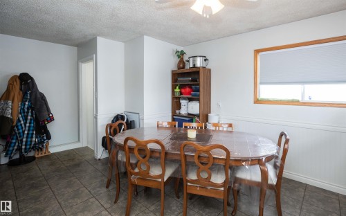 Dining area featuring tiled flooring, a window with a wood frame, and wainscoting - 4420 56 Avenue, Barrhead, AB - Indoor Photo Showing Dining Room