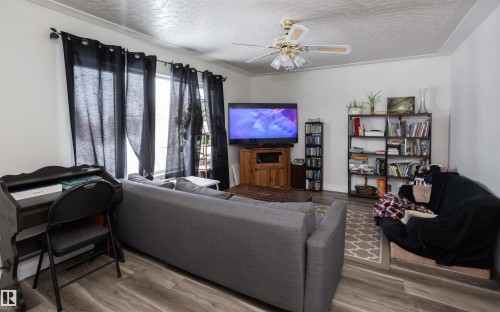 Living area featuring wood-look flooring, white walls, and a ceiling fan - 4420 56 Avenue, Barrhead, AB - Indoor