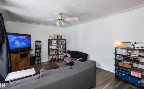 Living room with dark wood-style flooring, a ceiling fan with integrated lighting, and white walls - 4420 56 Avenue, Barrhead, AB - Indoor