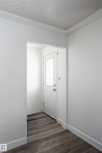 Entryway featuring a white door with decorative glass inserts and wood-look flooring - 4420 56 Avenue, Barrhead, AB - Indoor Photo Showing Other Room