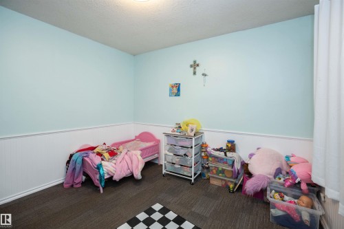 The room features light blue walls with white wainscoting and dark grey carpeted flooring - 4420 56 Avenue, Barrhead, AB - Indoor Photo Showing Bedroom