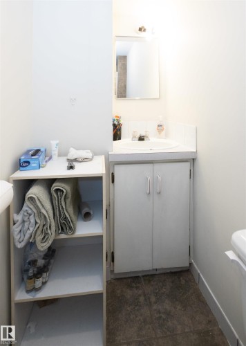 Bathroom featuring a vanity with an integrated sink and cabinet storage, a wall-mounted mirror, and tile flooring - 4420 56 Avenue, Barrhead, AB - Indoor Photo Showing Bathroom