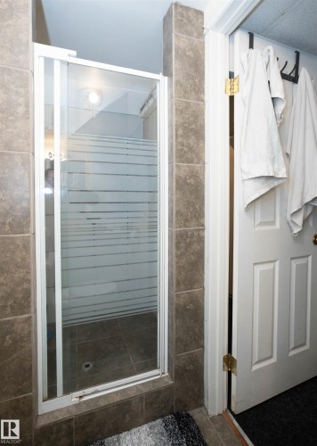 The bathroom features a shower enclosure with a sliding glass door and tiled walls - 4420 56 Avenue, Barrhead, AB - Indoor Photo Showing Bathroom