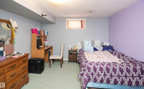 This room features light grey walls and a distinctive purple accent wall, providing a vibrant and versatile space - 4420 56 Avenue, Barrhead, AB - Indoor Photo Showing Bedroom