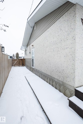 The property features a private side yard with a wooden fence and an exterior door - 4420 56 Avenue, Barrhead, AB - Outdoor With Exterior