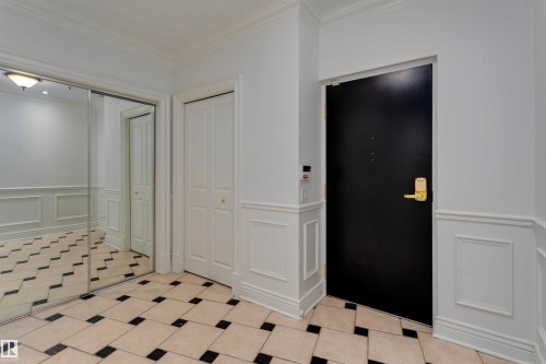 Entryway featuring a black and white tiled floor, white wainscoting, and crown molding - 102 11826 100, Edmonton, AB - Indoor Photo Showing Other Room
