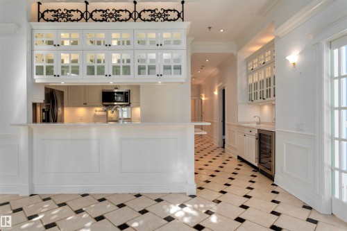 The kitchen features white cabinetry, a built-in microwave, and a stainless steel refrigerator - 102 11826 100, Edmonton, AB - Indoor Photo Showing Kitchen