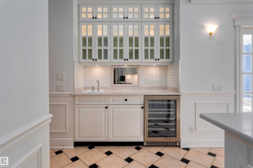 Wet bar area featuring white cabinetry, a sink, and a built-in beverage refrigerator - 102 11826 100, Edmonton, AB - Indoor