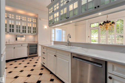 Kitchen featuring white cabinetry, a double sink, a stainless steel dishwasher, and a beverage refrigerator - 102 11826 100, Edmonton, AB - Indoor Photo Showing Kitchen