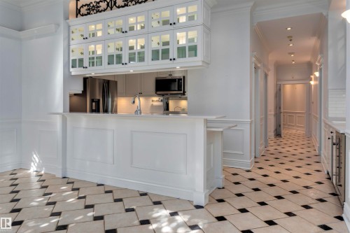 The kitchen features white cabinetry, stainless steel appliances, and a breakfast bar - 102 11826 100, Edmonton, AB - Indoor