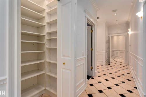 This property features a hallway with black and white checkered floor tiles, white wainscoting, and recessed lighting - 102 11826 100, Edmonton, AB - Indoor