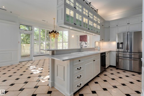 The kitchen features white cabinetry, stainless steel appliances, and a central island with a double sink and a countertop - 102 11826 100, Edmonton, AB - Indoor Photo Showing Kitchen With Upgraded Kitchen