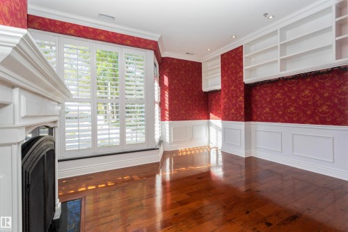 This room features hardwood floors, white wainscoting, and built-in shelving - 102 11826 100, Edmonton, AB - Indoor Photo Showing Other Room