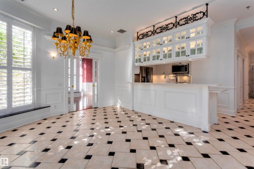 The property features an open-plan living area with checkered tile flooring, a gold chandelier, and large windows with plantation shutters - 102 11826 100, Edmonton, AB - Indoor Photo Showing Other Room