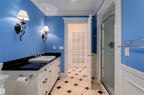 This bathroom features a white vanity with a black countertop, a white sink, and sconce lighting - 102 11826 100, Edmonton, AB - Indoor Photo Showing Bathroom