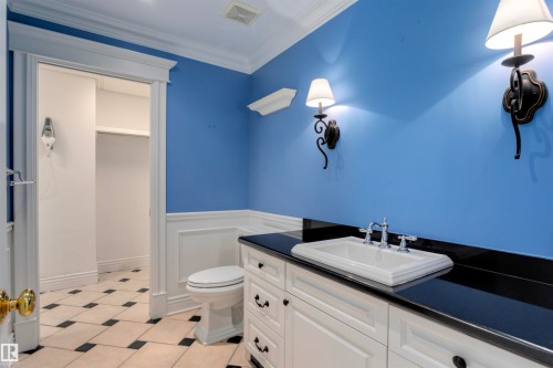 Bathroom featuring a white vanity with a black countertop and a white sink, sconce lighting, and a checkered floor - 102 11826 100, Edmonton, AB - Indoor Photo Showing Bathroom