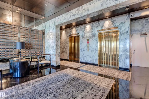 Lobby area featuring polished black floors, two gold-toned elevators, and marble-patterned wall coverings - 102 11826 100, Edmonton, AB - Indoor Photo Showing Other Room