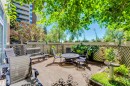 This property features a private patio area with a concrete surface, surrounded by lush green foliage and flowering plants - 102 11826 100, Edmonton, AB  - Outdoor 