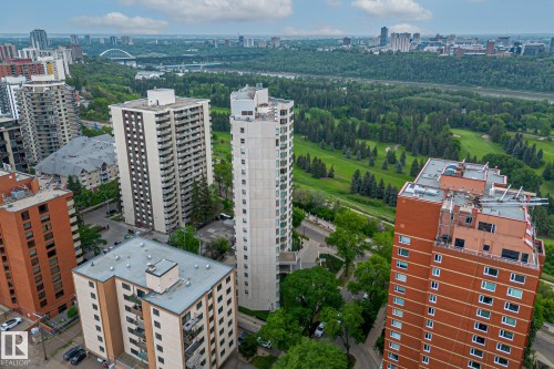 Aerial view of the property's surrounding environment, featuring a verdant landscape with extensive tree coverage and open green spaces - 102 11826 100, Edmonton, AB - Outdoor With Facade With View
