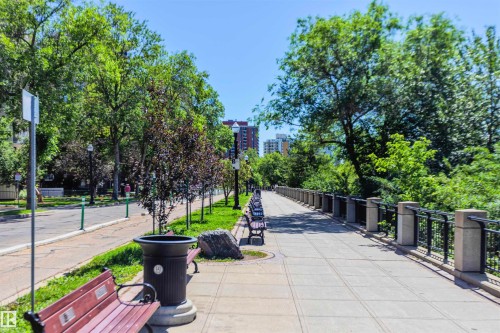 This community path offers a pleasant pedestrian experience, featuring a paved walkway, mature trees, and a protective railing - 102 11826 100, Edmonton, AB - Outdoor