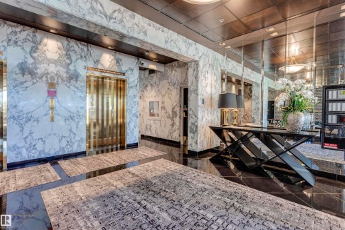 Elegant foyer featuring polished black flooring, white marble walls, and a golden elevator - 102 11826 100, Edmonton, AB -  Photo Showing Other Room