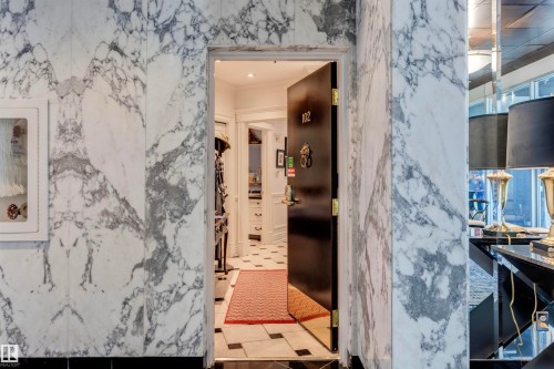 Entryway with a black door, white and grey marble walls, and black and white floor tiles - 102 11826 100, Edmonton, AB - Indoor Photo Showing Bathroom