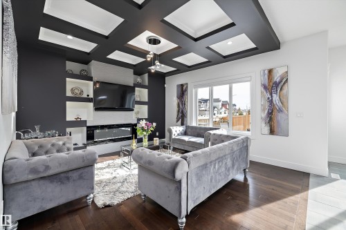 The living area features a coffered ceiling, hardwood floors, and a built-in media unit with a fireplace - 6303 169 Avenue, Edmonton, AB - Indoor Photo Showing Living Room With Fireplace