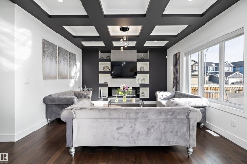 Living room featuring dark hardwood floors, a coffered ceiling with recessed lighting, and large windows providing natural light - 6303 169 Avenue, Edmonton, AB - Indoor