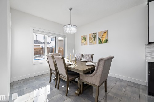 This dining area features a stylish chandelier, light-colored walls, and tile flooring - 6303 169 Avenue, Edmonton, AB - Indoor Photo Showing Dining Room