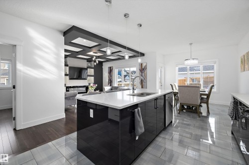 Modern kitchen featuring a large island with a sink, stainless steel appliances, and sleek dark cabinetry - 6303 169 Avenue, Edmonton, AB - Indoor Photo Showing Kitchen With Double Sink With Upgraded Kitchen