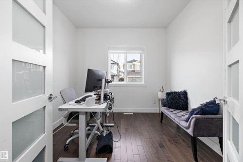 This versatile room features rich wood flooring, a window providing natural light, and a contemporary frosted glass panel door - 6303 169 Avenue, Edmonton, AB - Indoor Photo Showing Office